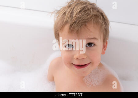 Il Toddler prendendo un bagno di bolle in vasca bianca Foto Stock