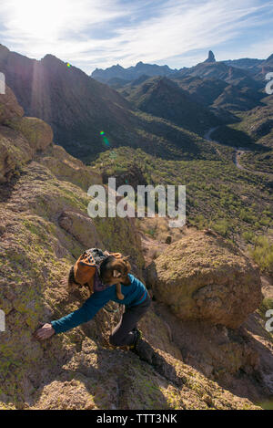 Elevato angolo di visione dell uomo che porta pastore tedesco in uno zaino mentre climbing mountain contro sky Foto Stock