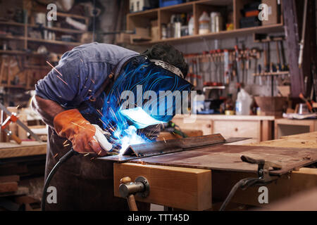 Lavoratore manuale di metallo di saldatura in officina Foto Stock