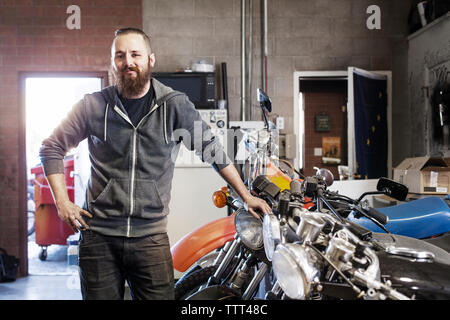 Ritratto di fiducia meccanico in piedi da moto al shop Foto Stock