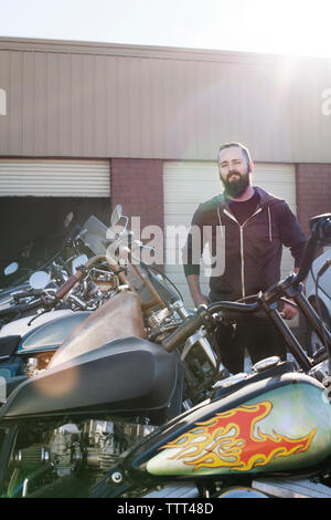 Fiducioso meccanico in piedi da moto al di fuori del negozio Foto Stock