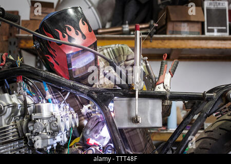 Grave meccanico di metallo di saldatura del motore del motociclo al negozio di riparazioni auto Foto Stock