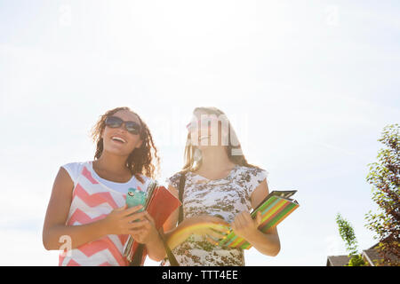 Basso angolo vista di amici a piedi contro il cielo chiaro sulla giornata di sole Foto Stock