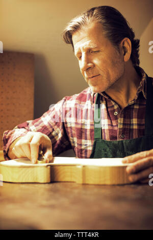 L'uomo esaminando violino in officina Foto Stock