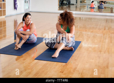 Happy amici di sesso femminile di parlare durante la seduta in palestra Foto Stock