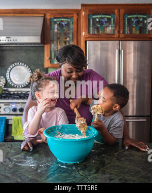 Madre sorridere mentre i bambini fanno i cookie insieme Foto Stock