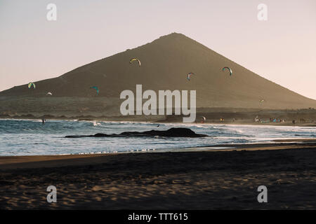Sagome di kitesurfer ed aquiloni sulla spiaggia al tramonto Foto Stock