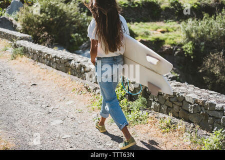 Una donna in abbigliamento casual cammina con una tavola da surf