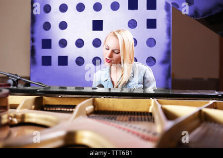 Giovane donna suonare pianoforte e canto in studio di registrazione Foto Stock