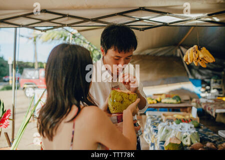 Paio di bere acqua di cocco in stallo del mercato Foto Stock