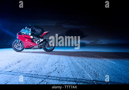 Biker rilassante sulla moto dalla parete di notte Foto Stock