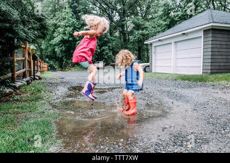 Giocoso sorelle jumping nella pozza Foto Stock