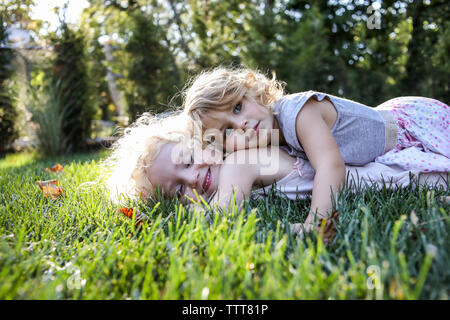 Sorelle giacente sul campo erboso a park Foto Stock