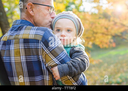 Premurosa ragazza che guarda lontano mentre viene portato dal nonno in posizione di parcheggio Foto Stock