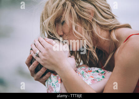 Donna con capelli biondi kissing figlia Foto Stock