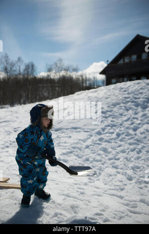 Ragazzo a giocare nella neve con pala in winter wonderland sulla giornata di sole Foto Stock