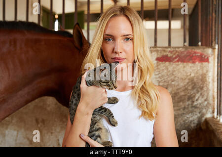 Ritratto di donna holding tabby cat in stabile Foto Stock