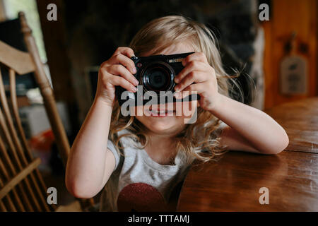 Il toddler girl imparare a scattare foto con una fotocamera Foto Stock