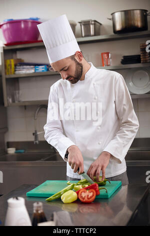 Lo Chef tritare verdure sul tagliere in cucina commerciale Foto Stock