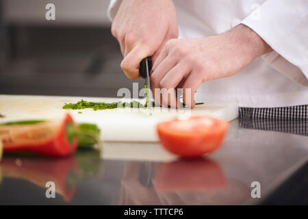 Close-up di chef tritare verdure sul bordo di taglio Foto Stock