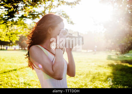 Vista laterale della donna fotografare attraverso il retro della fotocamera con stile Foto Stock