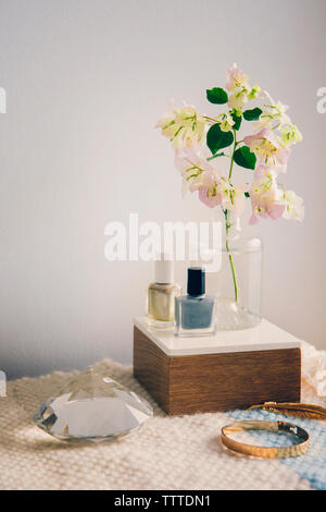 Smalto per unghie con gioielli e cristallo con vaso di fiori sul tavolo Foto Stock