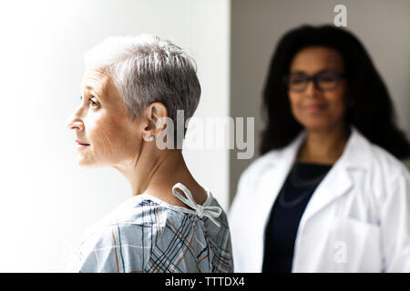 Riflessivo paziente femmina con medico in background Foto Stock