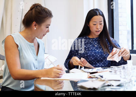 Designer di interni discutendo sul tessile durante la seduta in officina Foto Stock