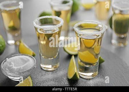 Colpi di tequila oro con fettine di lime e sale su un vassoio Foto Stock