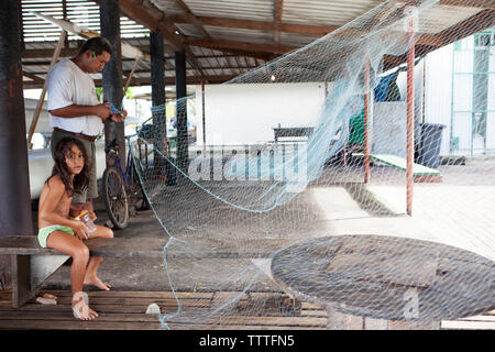 Polinesia francese, Tahiti. Un pescatore locale che fissa la sua Tutina in rete nel villaggio di Vairao situato lungo la costa meridionale dell'isola di Tahiti. Foto Stock