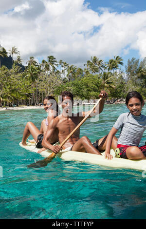 Polinesia Francese, Moorea. Giovani ragazzi in canoa a baia Opunohu. Foto Stock