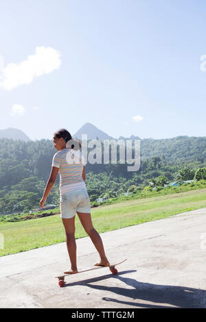 Polinesia Francese, Moorea. Bambini locali lo skateboard e mountain bike. Foto Stock