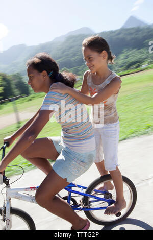 Polinesia Francese, Moorea. Bambini locali lo skateboard e mountain bike. Foto Stock