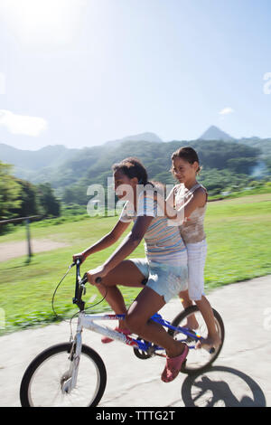 Polinesia Francese, Moorea. Bambini locali lo skateboard e mountain bike. Foto Stock