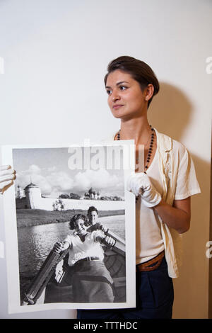 RUSSIA, MOSCA. Gallerista che mostra una fotografia in bianco e nero al Lumiere Fratelli Centro per la fotografia. Foto Stock