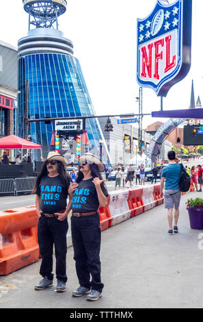 Anziani, maschi gemelli con i capelli lunghi che indossa abiti identici in piedi su Broadway in posa per una fotografia durante la cambiale di NFL 2019 Nashville Tennessee negli Stati Uniti. Foto Stock