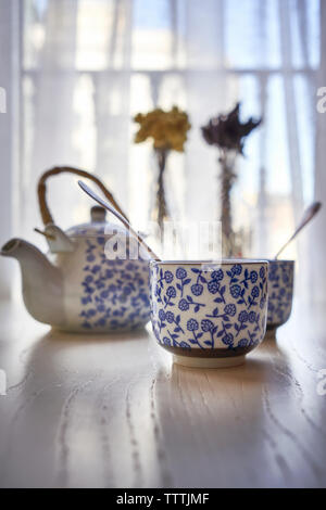 Cup a caldo con infusione di anice stellato e teiera in bianco su un tavolo di legno. Foto Stock