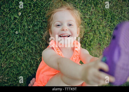 Ritratto ad angolo alto di ragazza felice carina che giace su campo erboso nel parco Foto Stock