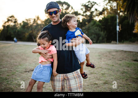 Ritratto di Padre giocoso che trasportano le figlie in posizione di parcheggio Foto Stock