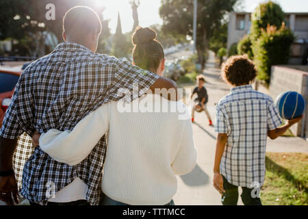Vista posteriore dei genitori con bambini che giocano su sentiero Foto Stock