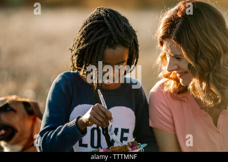 Parlando di madre in figlia mangiare seduti nella foresta Foto Stock