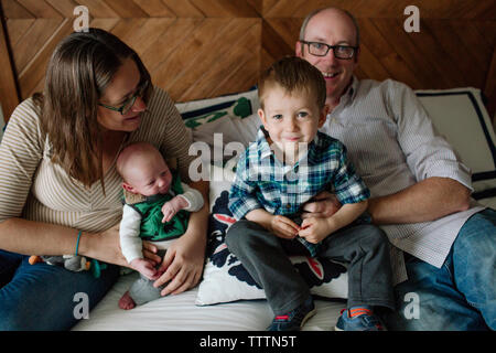 La famiglia felice con il neonato boy in appoggio sul letto di casa Foto Stock