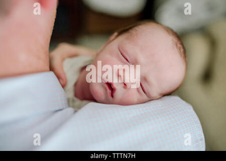 Close-up del padre che porta carino neonato figlio che dorme a casa Foto Stock