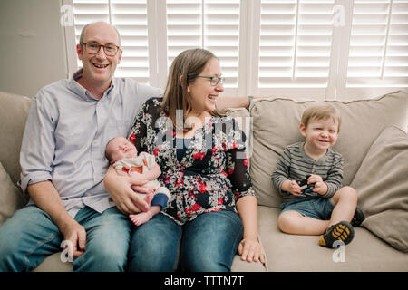 Giocoso famiglia felice seduto sul divano di casa Foto Stock