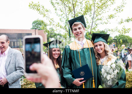 Immagine ritagliata della persona di fotografare gli studenti laureati alla cerimonia di consegna dei diplomi Foto Stock