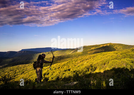 Uomo che ha di mira il tiro con l'arco nella foresta con arco e frecce Foto  stock - Alamy