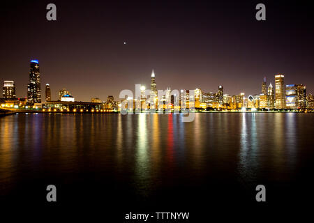 Paesaggio urbano illuminato dal Lago Michigan di notte contro sky Foto Stock