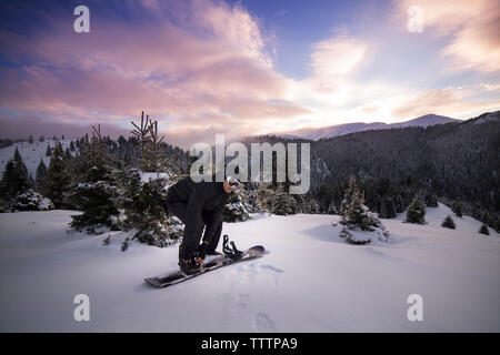 Uomo che indossa sci sulla montagna innevata contro sky Foto Stock