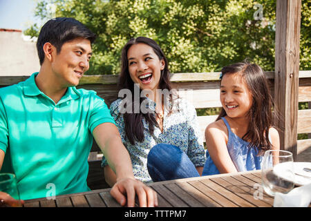 La famiglia felice seduta a tavola sul portico Foto Stock