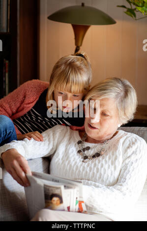 Nonna mostra magazzino alla nipote comodamente seduti sul divano di casa Foto Stock